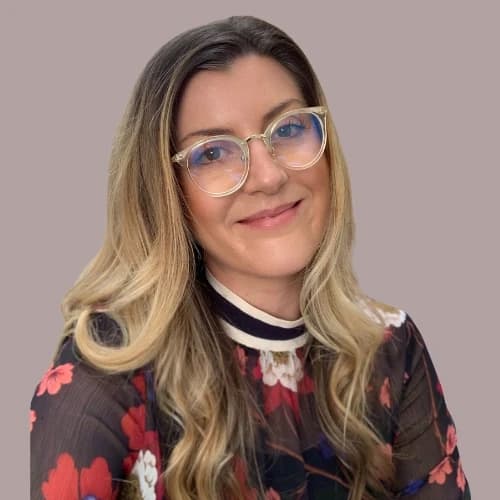 Lauren, wearing glasses and a floral-patterned top, smiling confidently